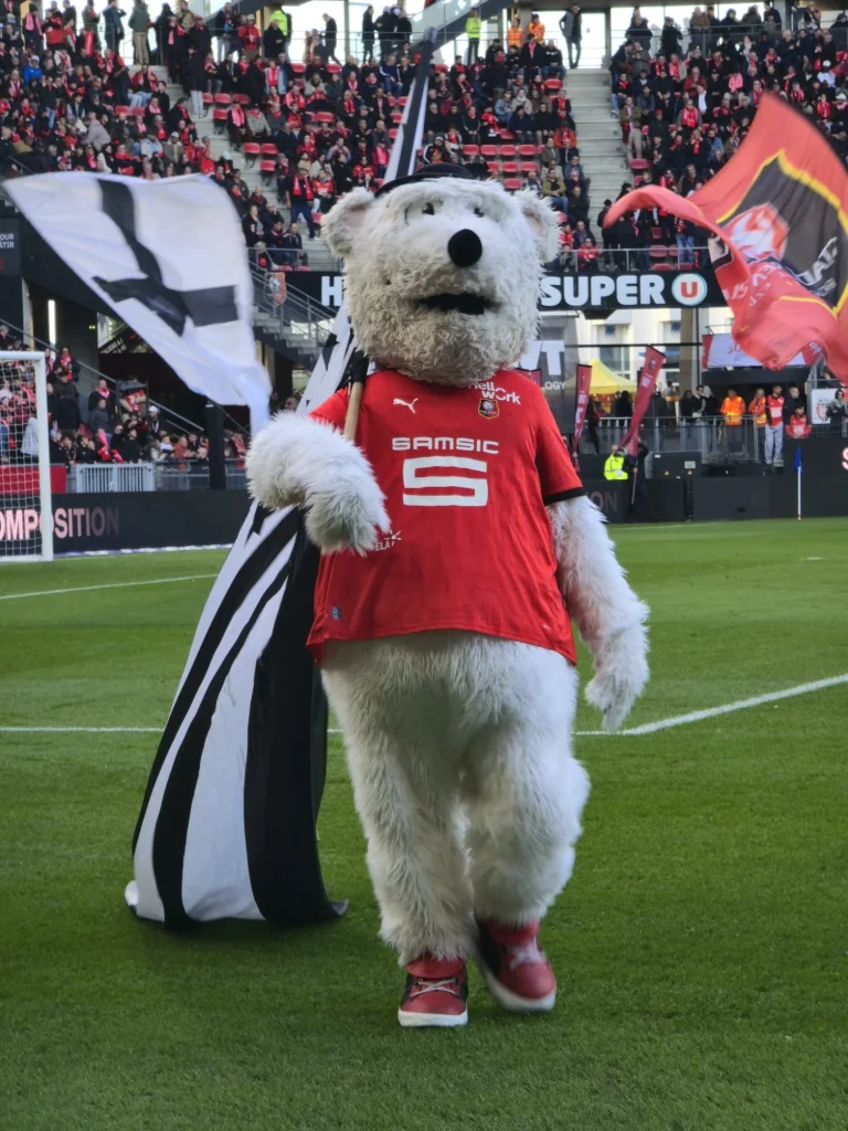 Erminig, la mascotte du Stade Rennais, sur la pelouse du Roazhon Park avec un drapeau breton