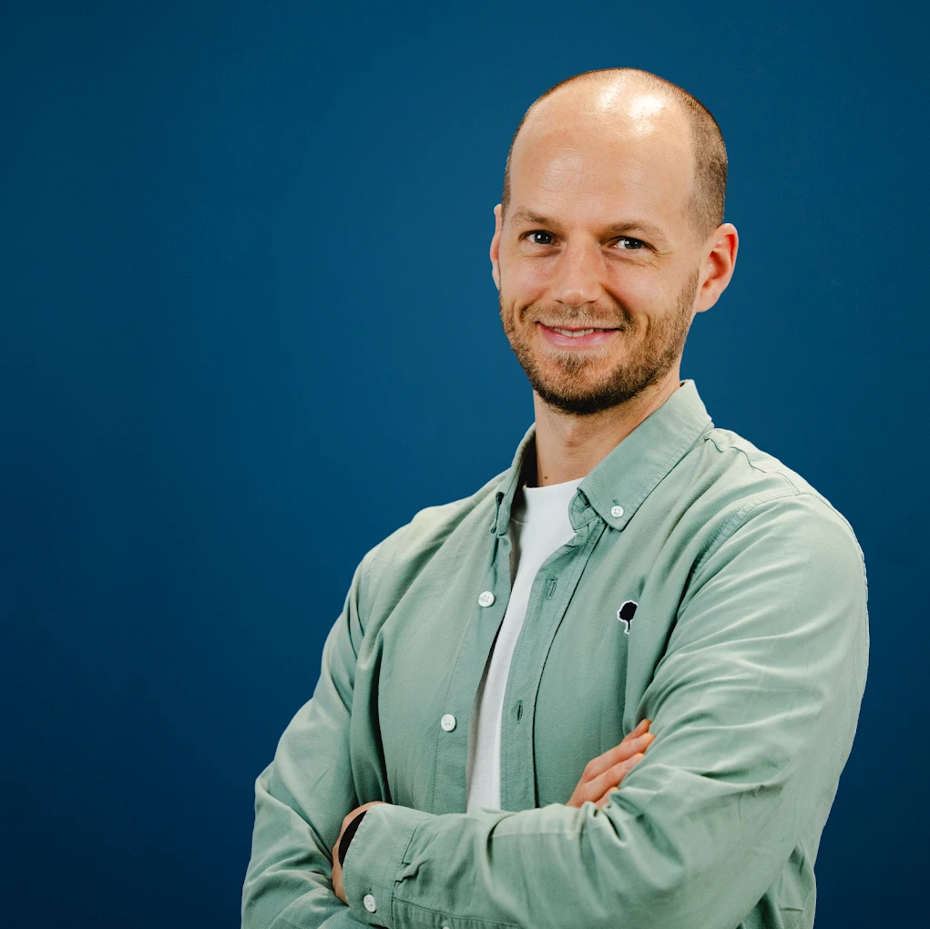 Jérémy Gohin, bras croisés et souriant, sur fond bleu